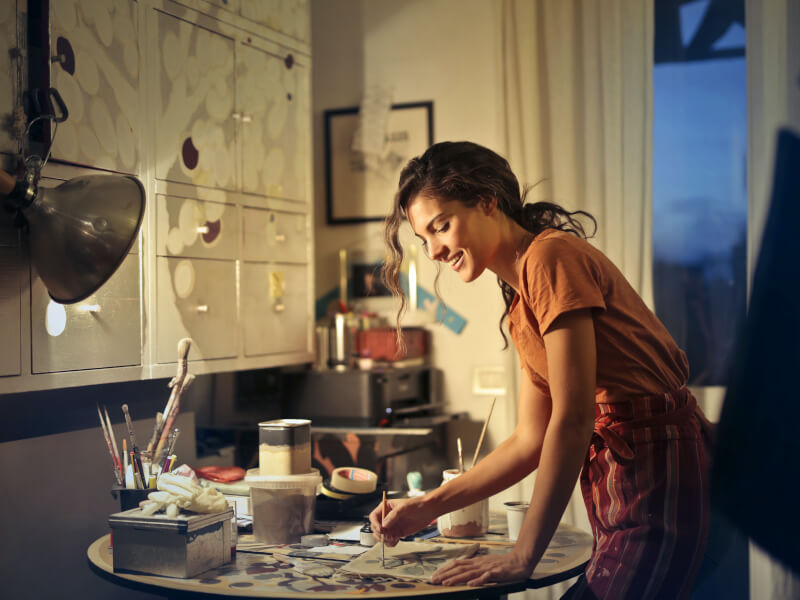 A woman enjoys a paint and sip at home.